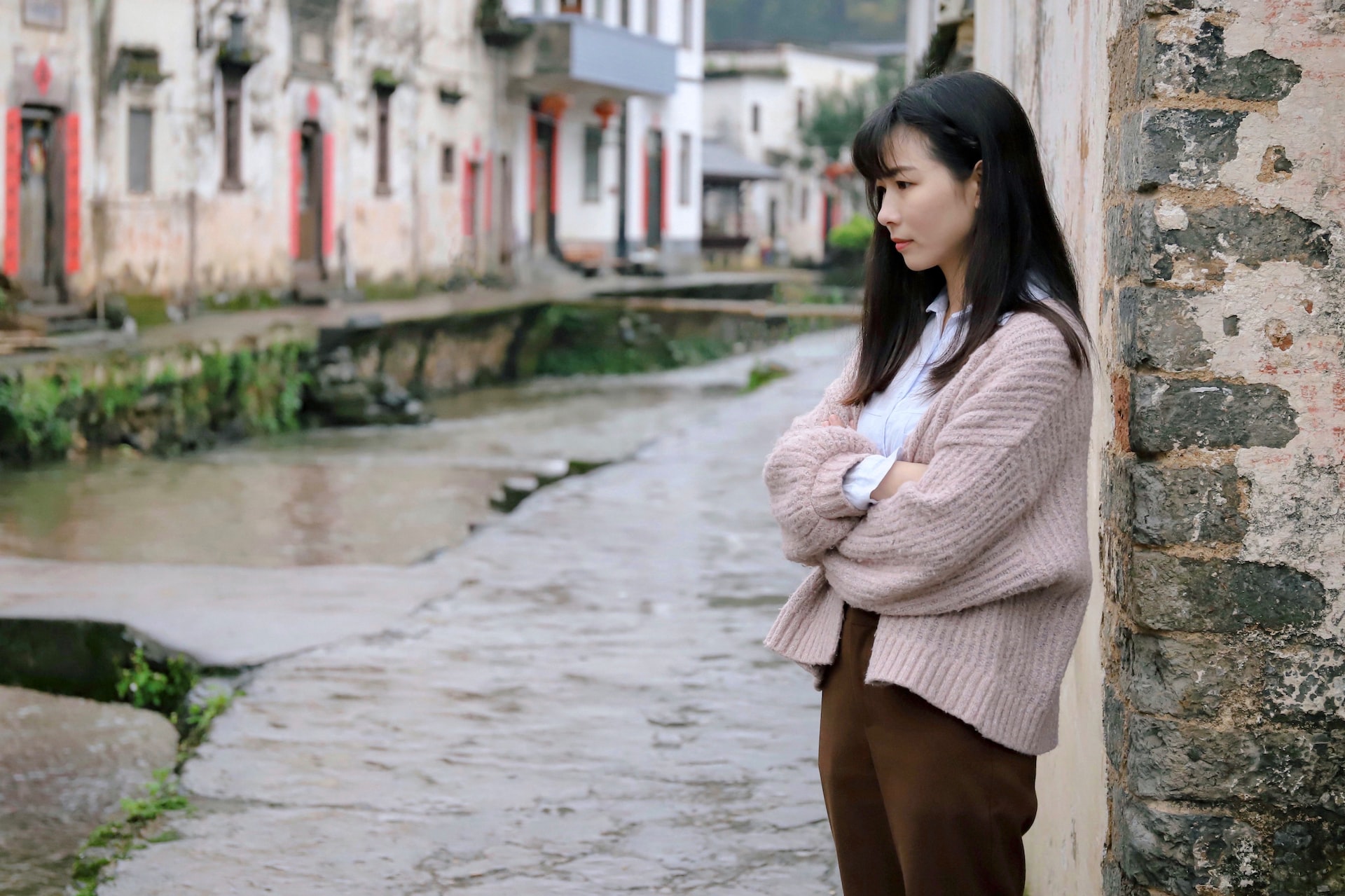 woman leaning on beige concrete wall